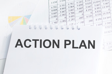 action plan text on notebook with stationery on wooden desk