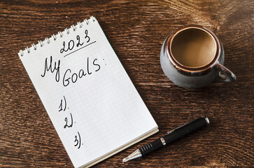 2023 goals list in a notebook with pen, setting New Year goals and resolutions