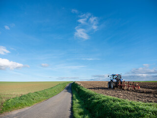 Fototapeta premium tractor and plow on field in rural belgian countryside near brussels