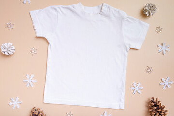 Baby t-shirt mockup for logo, text or design on pink background with winter decorations top view