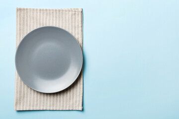 Top view on colored background empty round gray plate on tablecloth for food. Empty dish on napkin with space for your design