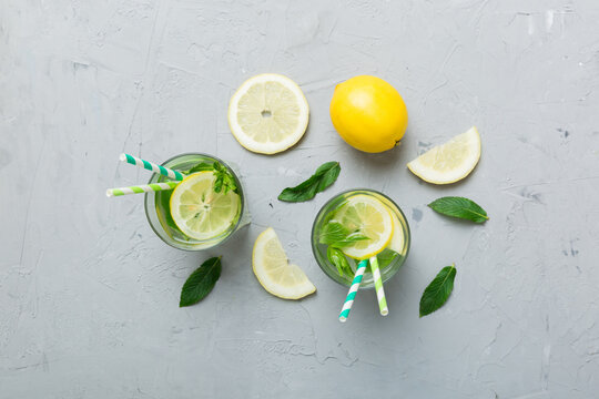 Caipirinha, Mojito cocktail, vodka or soda drink with lime, mint and straw on table background. Refreshing beverage with mint and lime in glass top view flat lay