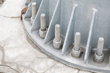 Bolts and nuts on a steel plate. Several bolts are firmly fixed on the metal base of the column to the concrete column