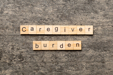 Caregiver burden word written on wood block. Caregiver burden text on cement table for your desing,...