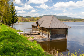 Obraz premium sluice house on the dam of the pond - wooden house on the water by the shore of the Olsina pond, Czech republic