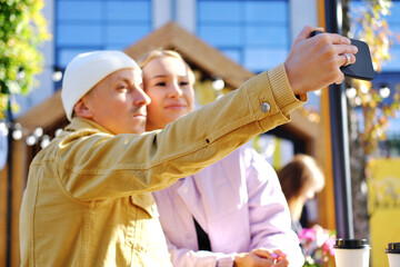 A couple in love, a guy and a girl, take a selfie together in sunny weather. couple looking at camera and smiling