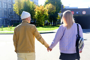 A couple in love, a guy and a girl, walks around the city and holds hands