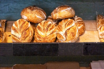 Rustic artisan sourdough bread loafs on a shelf in a bakery.
