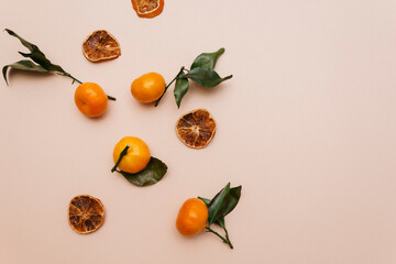 A composition of tangerines and dried candied fruits lie on a beige background. Christmas theme