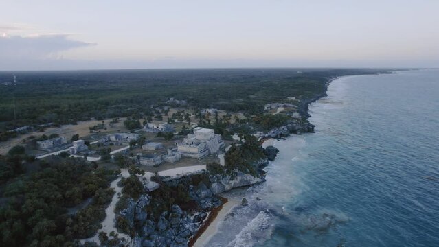 erial dolly drone shot of the coast in tulum mexico with rocks, sandy beach and the maya ruins with view to the cloudy sky 4K
