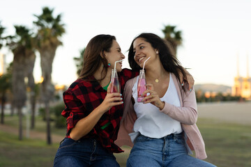 Beautiful lesbian young couple embraces. Girls drinking juice. LGBT community..