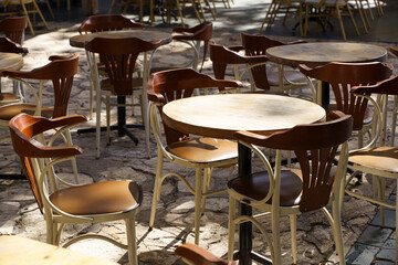 Street cafe in summer with wooden vintage chairs and tables on a tourist street. Empty restaurant or cafe without visitors.