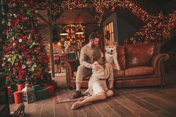 Candid authentic happy married couple spends time together with japanese dog at Xmas lodge