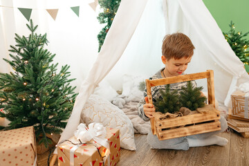 A little boy lying in a children's wigwam decorated for Christmas © fotofabrika