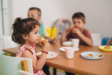 Young girl eats lunch in kindergarten