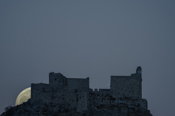 Obraz premium Hunting the full moon as it rises behind the ruins of the castle of Moclin, in the province of Granada, Spain.