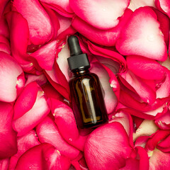 Rose fragrance oil in a bottle on rose petals.