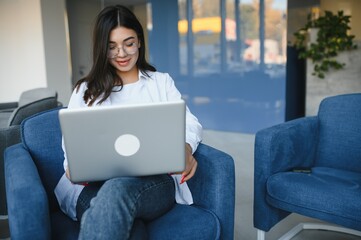 Naklejka premium Beautiful Caucasian woman dreaming about something while sitting with portable net-book in modern cafe bar, young charming female freelancer thinking about new ideas during work on laptop computer