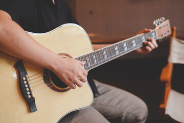 A close up of musician playing an acoustic guitar for entertainment or practicing for perfomance....