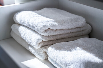 Neat stack of white soft towels in bathroom. Closet with clean folded textile for spa and hygiene....