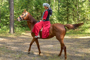 Woman in traditional clothes rides a horse in early spring