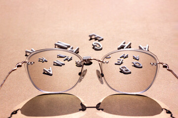 White letters in focus glasses on a brown background. Vision concept