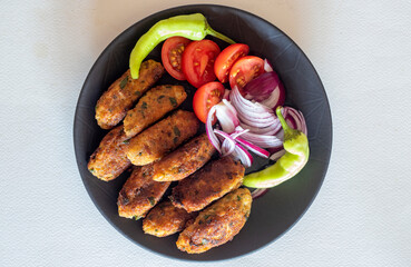 Fried vegetable patties on a plate. Homemade meatballs made of cauliflower garnished with fresh tomatoes, peppers and onions. Vegetarian lunch or dinner idea.vegetarian meatballs
