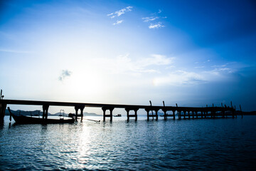 Fototapeta na wymiar silhouette of boat and bridge at sunlight in sea before sun set