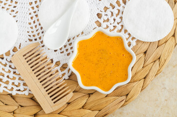 Orange fruit mask (scrub) in a small white bowl, hairbrush (comb) and cotton pads. Homemade hair,...