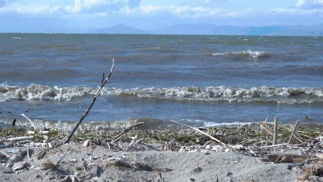 Close view Sevan lake in Armenia. Mountain lake in Armenia, Caucasus. 
Waves of water approach the polluted sand. Ecological problem.