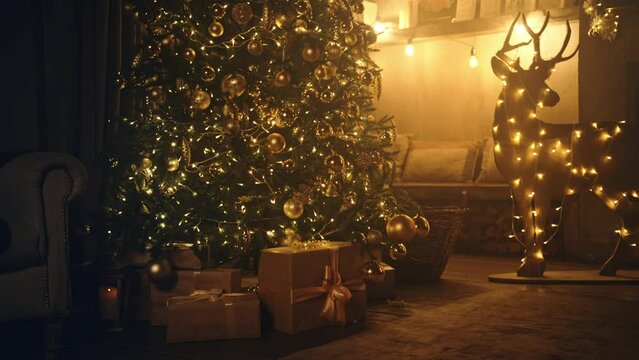 Christmas and New Year interior decoration. Green tree decorated with toys, gifts, present boxes, flashing garland, illuminated lamps. Fireplace with burning fire. Cozy Christmas atmosphere. 4K
