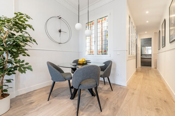 hallway-side dining room with round glass table, gray fabric upholstered chairs, leaded windows, and French oak flooring
