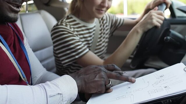 Driving school concept video. A car instructor teaches a young woman how to drive. Teaching the rules of the road and driving a vehicle