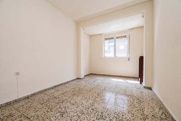Empty living room with glossy gray terrazzo flooring with off-white painted walls and window with roller blinds