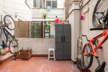 Fototapeta na wymiar Interior patio of a house with hanging bikes, terrace furniture and brown clay floors