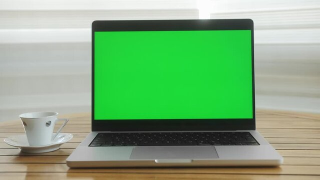 Laptop with green screen at home on a wooden table. Concept of learning and working online.