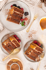 Delicious semi-naked chocolate cake with caramel topping and decorated with blackberries and raspberries. Light background