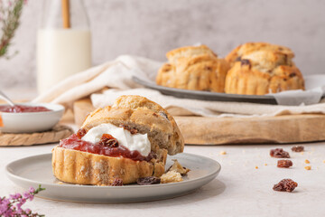 Homemade raisin scones with clotted cream and strawberry jam ready to eat