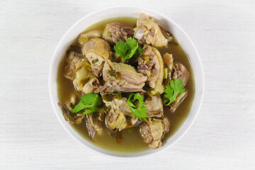 Homemade chicken soup with galangal,  lemon grass in white bowl.