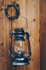 Old fashioned kerosene storm lamp hanging on wooden door