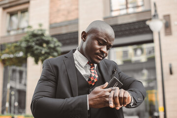 Portrait of black african american businessman in a suit with glasses and headphones stands against...