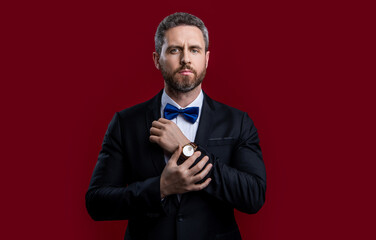 photo of tuxedo man in formal suit and wristwatch. formal tuxedo man isolated on red