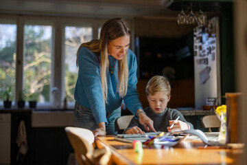 Mother helping son with homework at home
