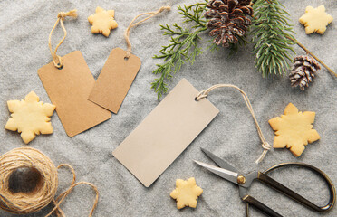 Blank gift tags with pine branch and Christmas cookies on textile background. The concept of preparing for the Christmas holiday