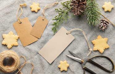 Blank gift tags with pine branch and Christmas cookies on textile background. The concept of...