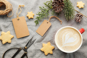 Blank gift tags with pine branch, cup of coffee and Christmas cookies on textile background. The...