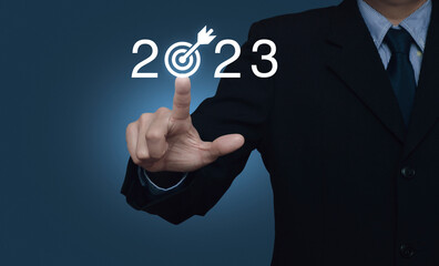 Businessman pressing 2023 letter with goal icon over light blue wall, Business happy new year 2023 success concept