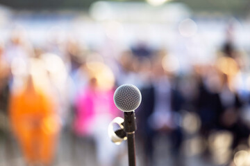 Microphone in the focus, blurred people in the background. Public speaking concept.