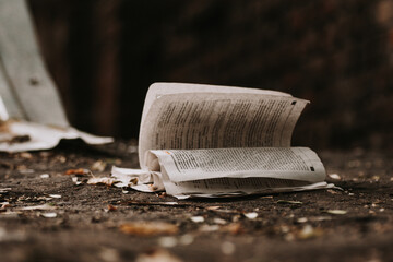 open book and crumpled pages on the dirty ground.