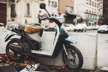 an old motorcycle, rusty and broken, abandoned in the middle of the city.